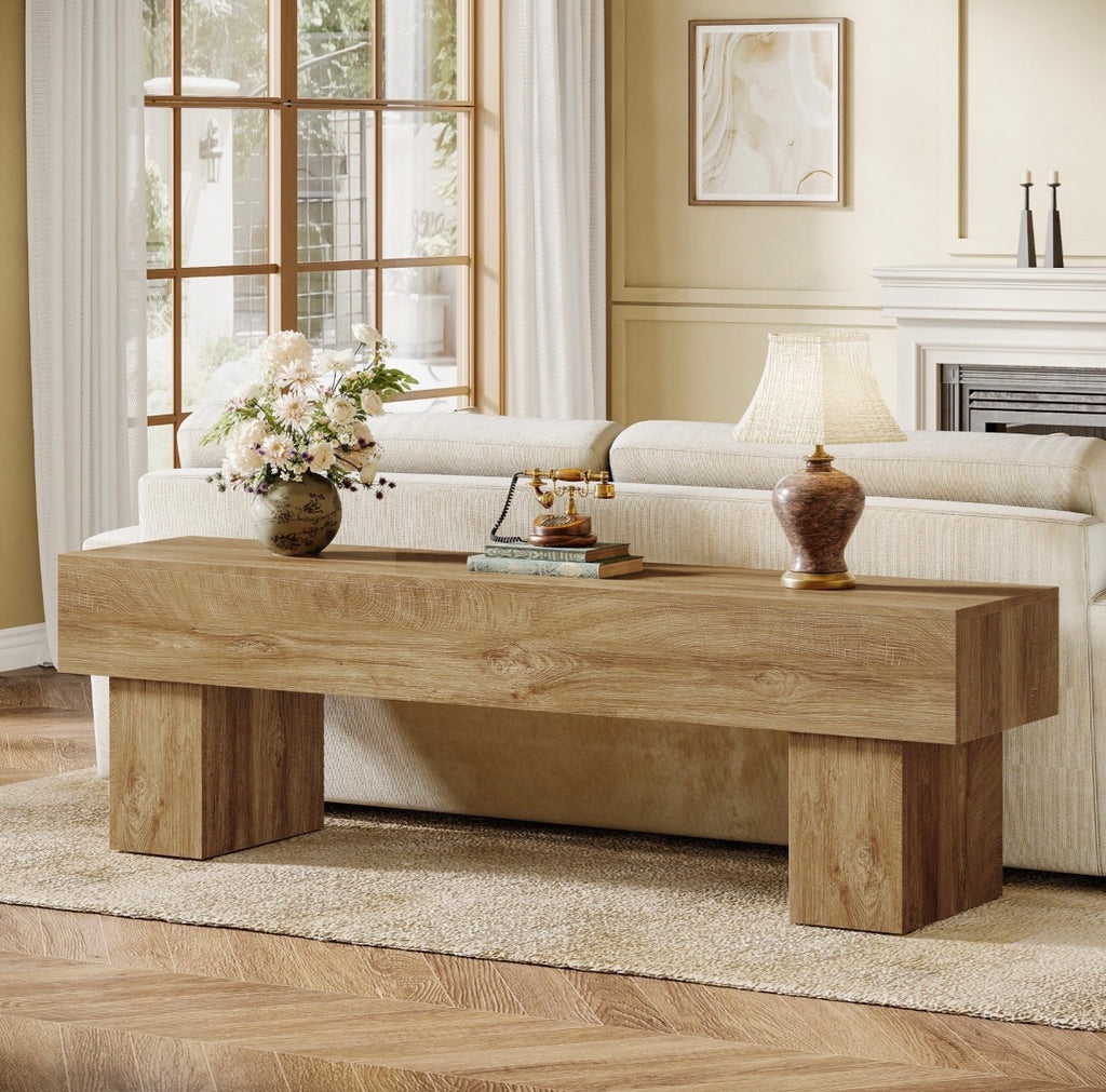 Light oak TV console table with wide top and sturdy block legs beneath framed TV